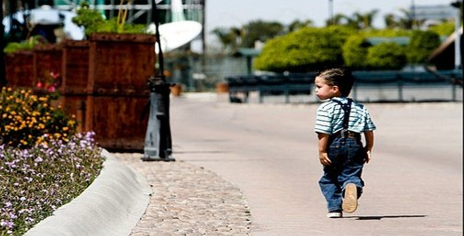 A young child walking down the street

Description automatically generated