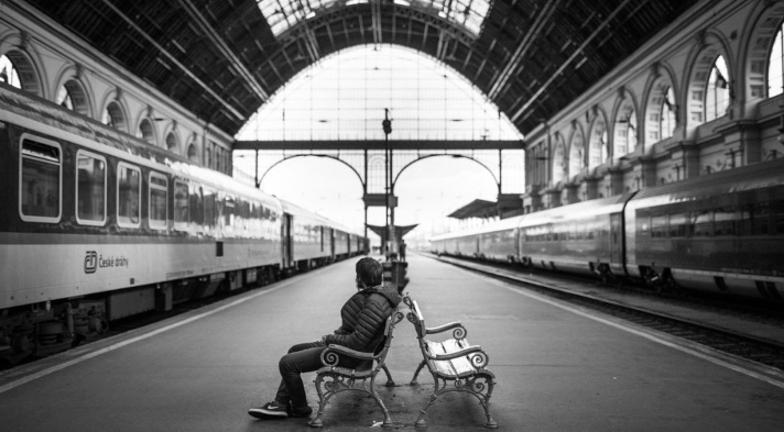 A person sitting on a bench in a train station

Description automatically generated