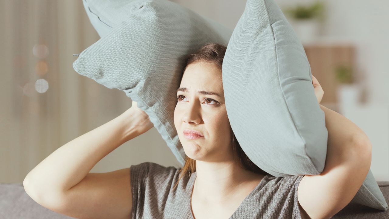 A person holding a pillow over her head

Description automatically generated